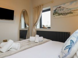 A bedroom with a bed, towels, and a television at Pistyll Ddu in Brynsiencyn near Llanfairpwllgwyngyll