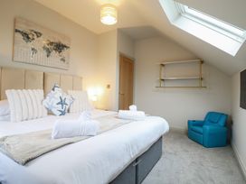 A bedroom with a bed and blue chair at Pistyll Ddu Brynsiencyn near Llanfairpwllgwyngyll