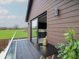 A balcony with a table and champagne bucket at Pistyll Ddu Brynsiencyn near Llanfairpwllgwyngyll