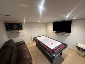 A game room with air hockey table, dartboard, and sofa at Pistyll Ddu, Llanfairpwllgwyngyll