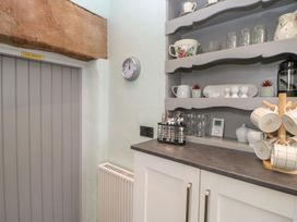 A kitchen with shelves and a clock at Orchard Cottage in Appleby-in-Westmorland