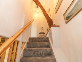 A staircase with a wooden handrail and light fixture at Orchard Cottage in Appleby-in-Westmorland