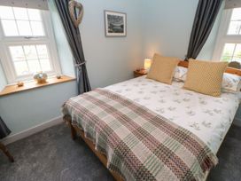 A bedroom with a bed and windows at Orchard Cottage in Appleby-in-Westmorland