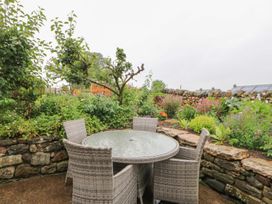 A garden with a table and chairs surrounded by flowers at Orchard Cottage in Appleby-in-Westmorland