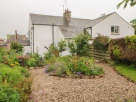 A garden with flowers and a gravel pathway at Orchard Cottage in Appleby-in-Westmorland