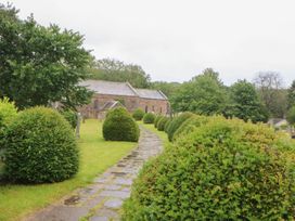 A pathway lined with bushes leading to a building at Orchard Cottage in Appleby-in-Westmorland