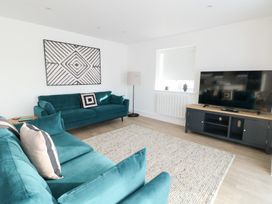 A living room with a television and blue sofas at Glynllifon 4 in Marianglas