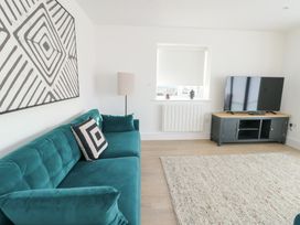 A living room with a sofa and television at Glynllifon 4 in Marianglas