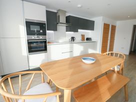 A kitchen with appliances and a dining table at Glynllifon 4 in Marianglas