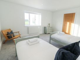 A bedroom with two beds and a chair at Glynllifon 4 in Marianglas