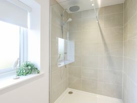 A shower with a tiled wall and window at Glynllifon 4 in Marianglas