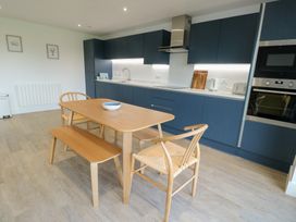 A kitchen with a table and chairs at Glynllifon 6 in Marianglas