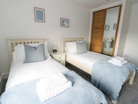 A bedroom with two single beds and a nightstand at Glynllifon 6 in Marianglas