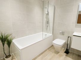 A bathroom with a bathtub, shower, toilet, and sink at Glynllifon 6 Marianglas