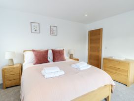 A bedroom with a bed and side tables at Glynllifon 6 in Marianglas