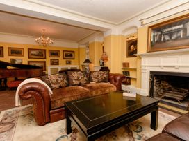 A living room with a sofa, coffee table, and piano at Ladye Park in Liskeard