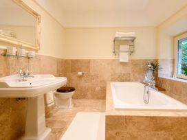 A bathroom featuring a sink, toilet, bath tub, and mirror at Ladye Park in Liskeard