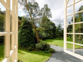 A view of a garden with trees and a pathway from a window at Ladye Park in Liskeard