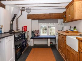 A kitchen with a stove and wooden cabinets at Old Sunday School in Welcombe near Kilkhampton