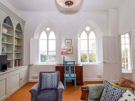 A living room with a sofa, armchair, and desk at Old Sunday School in Welcombe near Kilkhampton