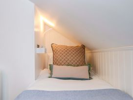 A bed with pillows and a light fixture in a bedroom at Old Sunday School in Welcombe near Kilkhampton