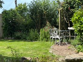 A garden with grass, a bench, table, and flowers at Old Sunday School in Welcombe