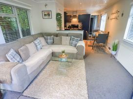 A living room with a sofa and glass table at Evermore Lodge, 48 Calgarth Park, White Cross Bay, Windermere
