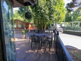 An outdoor deck area with a table and chairs at Evermore Lodge, 48 Calgarth Park, White Cross Bay, Windermere