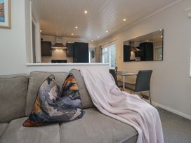 A living room with a sofa and dining area at Evermore Lodge, 48 Calgarth Park, White Cross Bay, Windermere