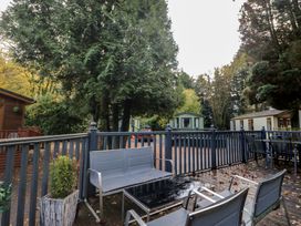 A deck area with seating and surrounding trees at Evermore Lodge, 48 Calgarth Park, White Cross Bay, Windermere