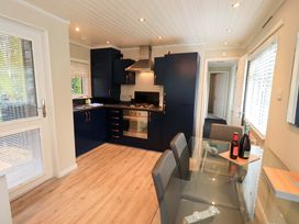 A kitchen with cabinets, stove, dining table and chairs at Evermore Lodge, 48 Calgarth Park, White Cross Bay, Windermere