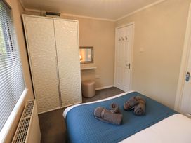 A bedroom with a bed and wardrobe at Evermore Lodge, 48 Calgarth Park, White Cross Bay, Windermere