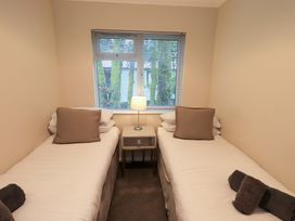 A bedroom with two beds and a lamp at Evermore Lodge, 48 Calgarth Park, White Cross Bay, Windermere