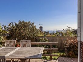 A garden with a wooden table and chairs overlooking the sea at Woodbury in Teignmouth