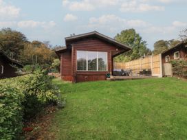 A cabin with a deck and grass area at Woodlands View in Leek