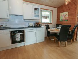 A kitchen with white units and a dining table at Woodlands View in Leek