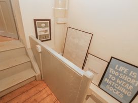 A staircase with framed pictures and a light fixture at Rock Cottage in Milnthorpe