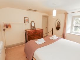 A bedroom with a bed and a wooden dresser at Rock Cottage in Milnthorpe