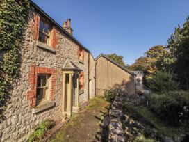 An exterior view of a stone cottage with a porch and a shed at Rock Cottage in Milnthorpe