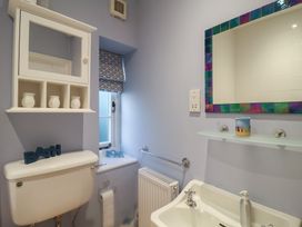 A bathroom with a toilet, sink, and shelf at Nutshell in Aldeburgh