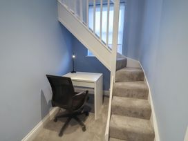 A home office with a desk and chair under stairs at Nutshell in Aldeburgh