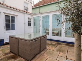 A garden with a glass table and plants at The Nutshell in Aldeburgh