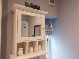 A cabinet with a mirror and vases in a bathroom at The Nutshell in Aldeburgh