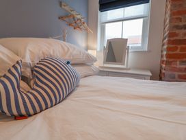 A bedroom with a striped whale pillow on the bed at The Nutshell in Aldeburgh