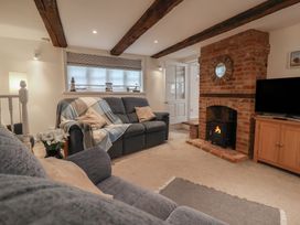 A living room with a sofa, fireplace, and television at The Nutshell, Aldeburgh