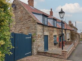 An outdoor view of a stone cottage with a blue gate at Dove Cottage in Sneaton near Ruswarp