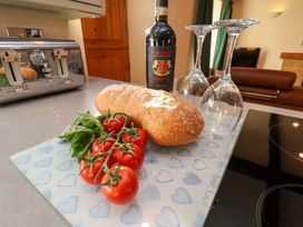 A kitchen featuring bread, tomatoes, a wine bottle with glasses at Dove Cottage Sneaton near Ruswarp