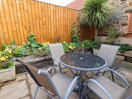 A garden with a table and chairs surrounded by flowers at Dove Cottage in Sneaton near Ruswarp