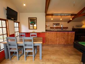 A man cave with a bar, table, chairs, and television at Dove Cottage in Sneaton near Ruswarp