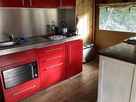 A kitchen with red cabinets and stainless steel appliances at Camnant near Newcastle Emlyn